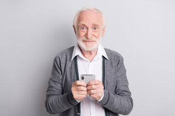 Portrait of old white hair optimistic man hold telephone wear dark sweater isolated on grey background