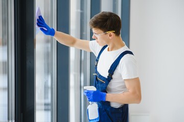 Cleaning service came to clean new house. Hardworking man carefully clean window. Side view