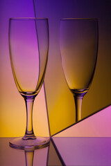 Abstract still life with a glass in purple and yellow tones.Beautiful wine glass with pink, yellow and blue lit background. Art idea.