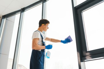 Cleaning service came to clean new house. Hardworking man carefully clean window. Side view