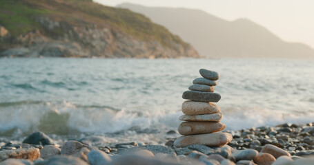Balanced pebble pyramid on the beach at sunset
