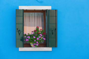 Open Window shutters  and flowers on blue wall, Burano, Venice