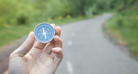 Traveler holding compass in road background.