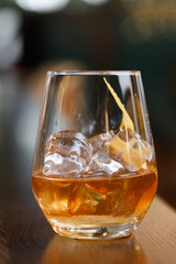 A glass of whiskey on the rocks on the bar. A glass of strong alcohol close - up in macro.