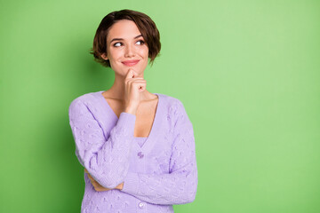 Portrait of positive pretty lady arm on chin look empty space purple outfit isolated on green color...