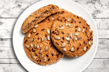 Fresh oatmeal cookies, gingerbread on a plate on a wooden background. Oatmeal gingerbreads sprinkled with sunflower and flax grains close up