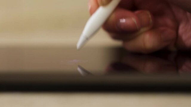 Close up of female freelancer or graphic designer working on a digital tablet using stylus pen. Concept. Woman hand writing on a graphic tablet, side view. 