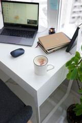 Office desk with laptop and coffee cup at home