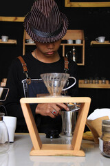 Indonesian Barista Prepare coffee drinks for customers at the coffee shop. portrait of a coffee shop employee making coffee at the bar. the process of making warm drinks with a vintage color concept