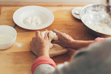 Female hands preparing homemade bread.  Elderly woman in kitchen knead the dough until it is smooth.