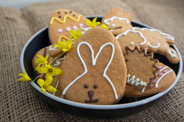 Easter holiday cookies servet on dish on the table with jute tablecloth, group of color painted gingerbread sweets springtime