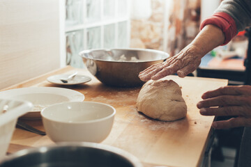 Female hands preparing homemade bread.  Elderly woman in kitchen knead the dough until it is smooth.