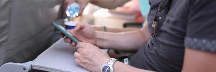 Man holds phone in his hands while sitting chair in airplane. Rules for using electronic gadgets while flying on airplane