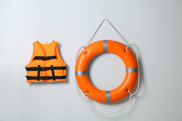 Orange life jacket and lifebuoy on light background. Rescue equipment