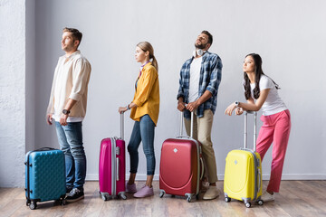 Multiethnic people with suitcases waiting in hall of airport