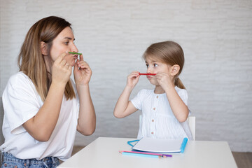 Speech therapy for kids. Young woman and little girl make exercises, activities and game for better...
