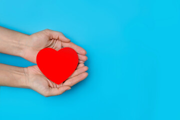 Fototapeta premium heart in the hands of a person on a blue background copy space, the concept of support, kindness and charity