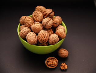 Walnuts in green bowl. Whole walnuts. Walnut kernel on black background. Walnut healthy food.