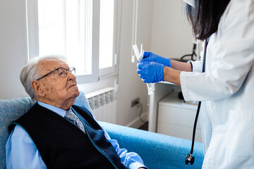 Nurse performing a coronavirus pcr test on an elderly man in his home