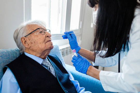 Nurse Performing A Coronavirus Pcr Test On An Elderly Man In His Home