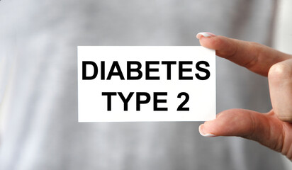 The girl holds a card with the text DIABETES TYPE 2, the background is a gray T-shirt.