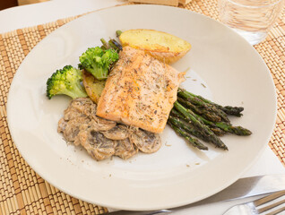 dish of fried river trout fillet with garnish of broccoli, asparagus sprouts and mushroom sauce