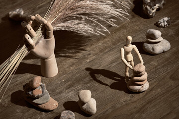 Wooden model hand holding dry withered pampas grass. Human figure building zen stone pyramids....