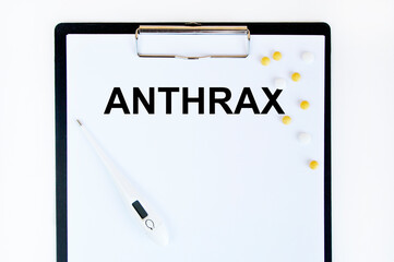 On the tablet for writing the text of ANTHRAX, next to the thermometer and yellow tablets.