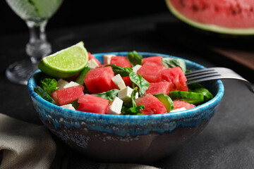 Delicious salad with watermelon served on black table, closeup