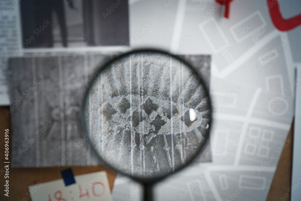 Sticker Looking through magnifying glass at photo of footprint on detective board, closeup