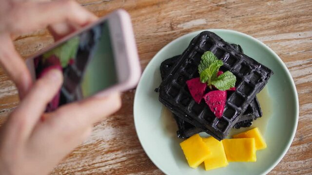 Top view of hands taking a picture of Belgian waffles with smartphone. 