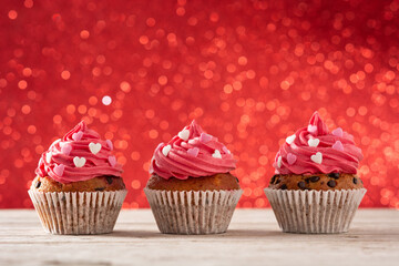 Cupcakes decorated with sugar hearts for Valentine's Day on red background	