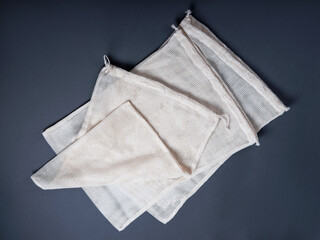 Three white zero waste string sacks for fruits, vegetables, groceries or other products on the grey...
