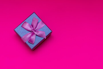 Gift box with ribbon on a pink background. Composition for Valentine's Day. Flat lay, copy space, top view.