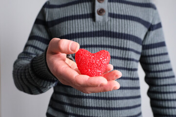 young guy in jacket holding a red heart model in his hand, a symbol of love, concept of confession,...
