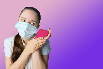 girl in white blouse and a medical mask holding red heart model in her hands, symbol of love, concept of confession, Valentine's Day, cardiology