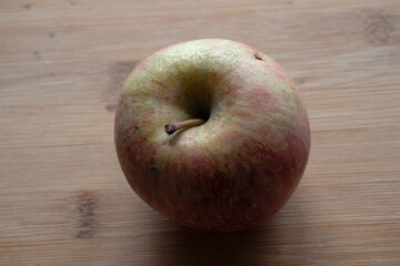 One Apple on Tabletop, Top View. Apple on a wooden surface. Apple on a wooden countertop. Red Green Apple
