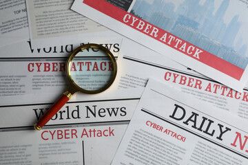 Newspaper with headline CYBER ATTACK and magnifying glass, top view - obrazy, fototapety, plakaty