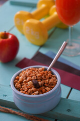 Healthy food fitness and health breakfast homemade granola with nuts, fresh orange juice, dumbbells on blue background  