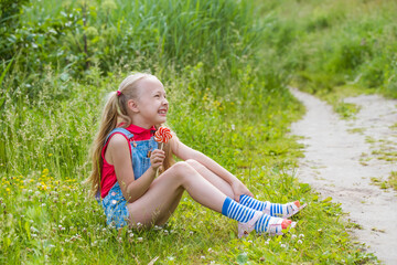 Blonde little girl with long hair and candy on a stick