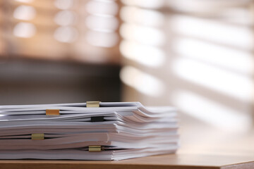 Stack of blank paper with binder clips on wooden table indoors. Space for text