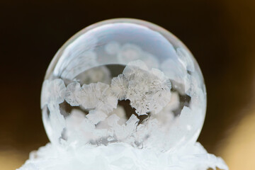 A frozen bubble in the snow with bokeh in the background. Beautiful frosty patterns on a frozen soap bubble. close-up, isolate on blurred background