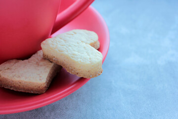 Red cup of coffee and heart shaped cookies on gray concrete background. 