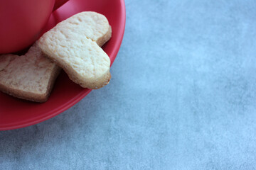 Red cup of coffee and heart shaped cookies on gray concrete background. 