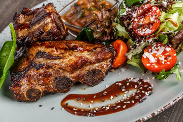 Fried ribs with rosemary, onion, sauce on a concrete background. Dark table. Place for text,...