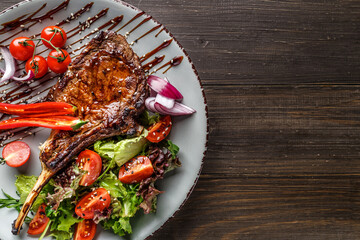 Grilled beef steak, herbs and spices on a dark table. Top view. Free space for your text.