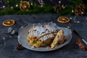 Christmas Stollen against the background of spruce branches and gray concrete