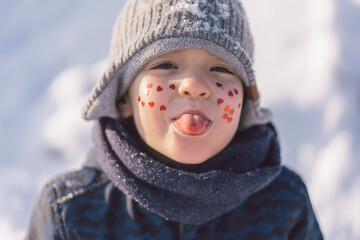 Joyful boy with red hearts on his face. Love concept