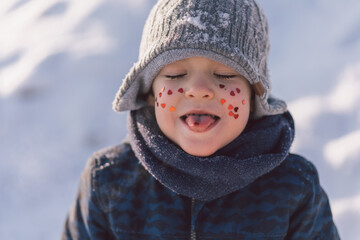 Joyful boy with red hearts on his face. Love concept