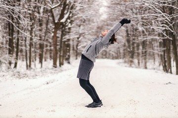 Fit sportsman doing warm up exercises at snowy winter day in forest. Winter fitness, healthy life